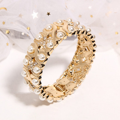 Women`s bracelet in golden color with pearls and stones