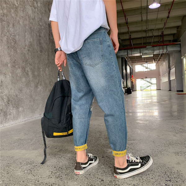 Modern férfi farmer, szakadt motívumokkal és kék színű feliratokkal