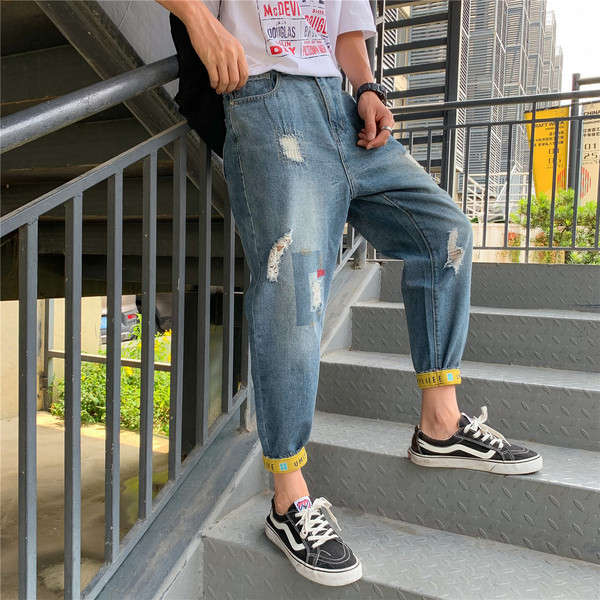 Modern férfi farmer, szakadt motívumokkal és kék színű feliratokkal