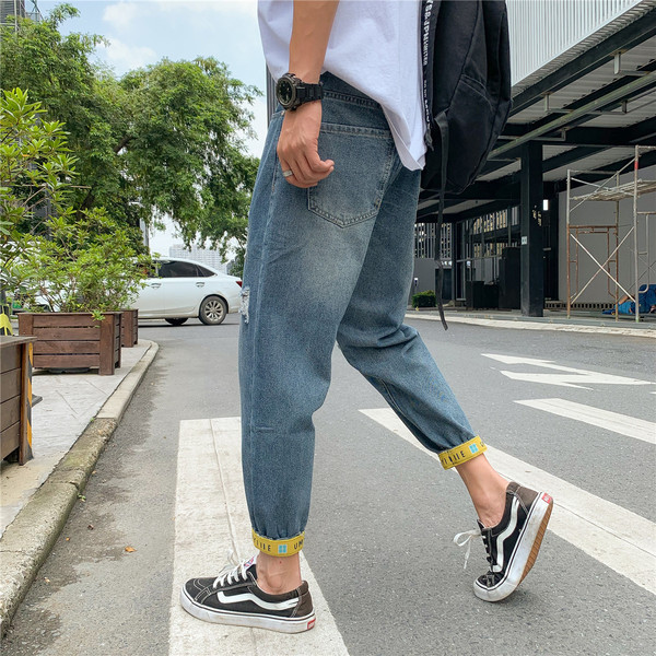 Modern férfi farmer, szakadt motívumokkal és kék színű feliratokkal