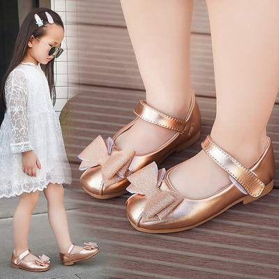 Modern children`s shoes with ribbons in black and gold