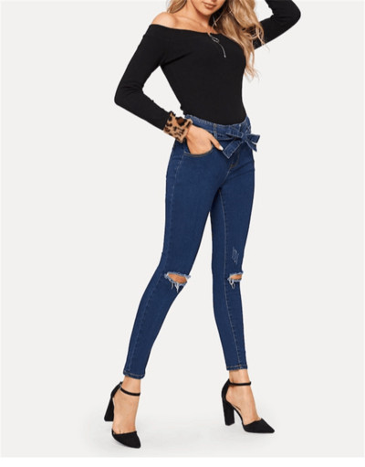 Modern női hosszú farmer szakadt motívumokkal és kék övvel