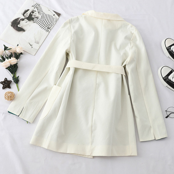 Stílusos női kabát fekete-fehér övvel és zsebekkel