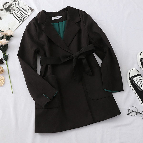 Stílusos női kabát fekete-fehér övvel és zsebekkel