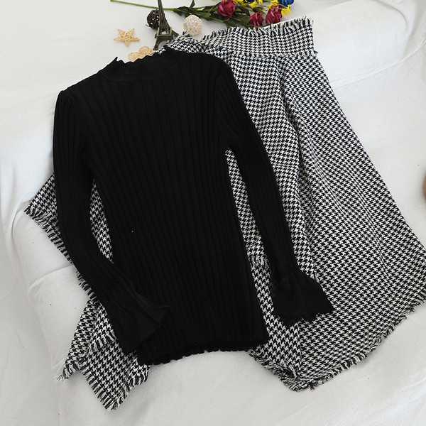 Női szett, mely tartalmaz egy fekete pulóvert és egy kockás szoknyát magas derékkal