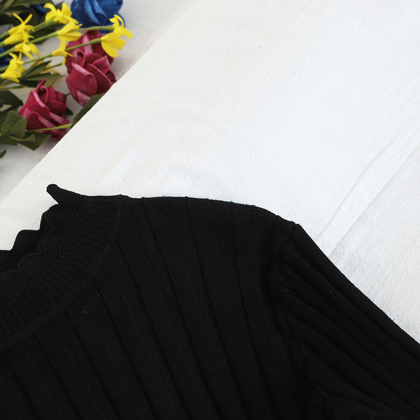 Női szett, mely tartalmaz egy fekete pulóvert és egy kockás szoknyát magas derékkal