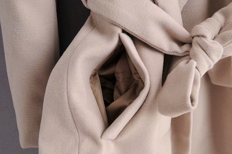 Hosszú női kabát övvel és bézs zsebekkel