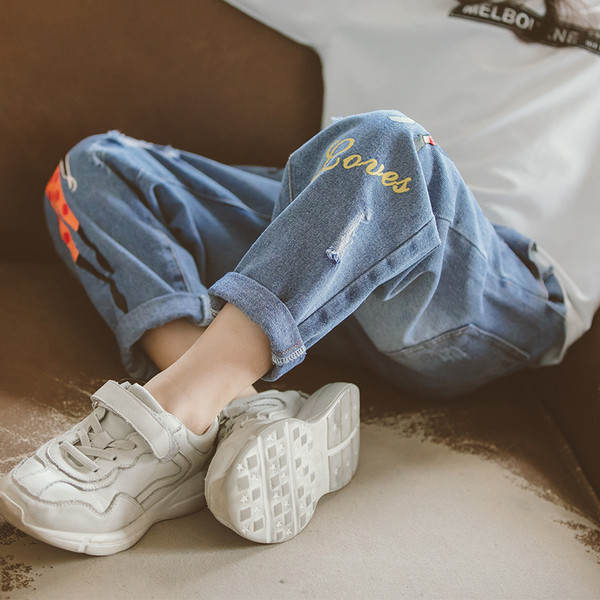 Blugi moderni pentru copii cu motive rupte si aplicatii in albastru si negru pentru fete