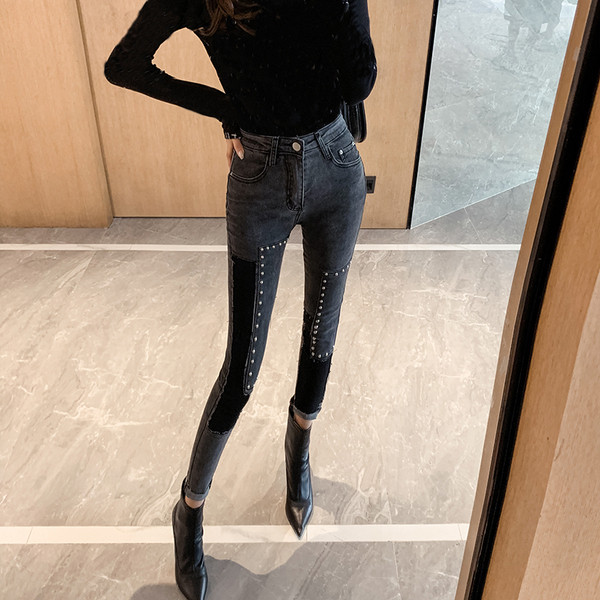 Sötét színű, testhezálló női farmer, magas derékkal és fémszegecsekkel