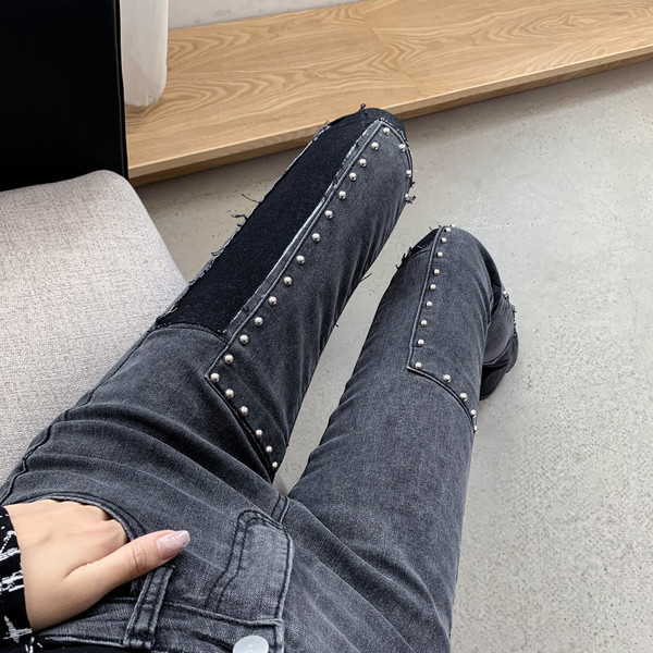 Sötét színű, testhezálló női farmer, magas derékkal és fémszegecsekkel