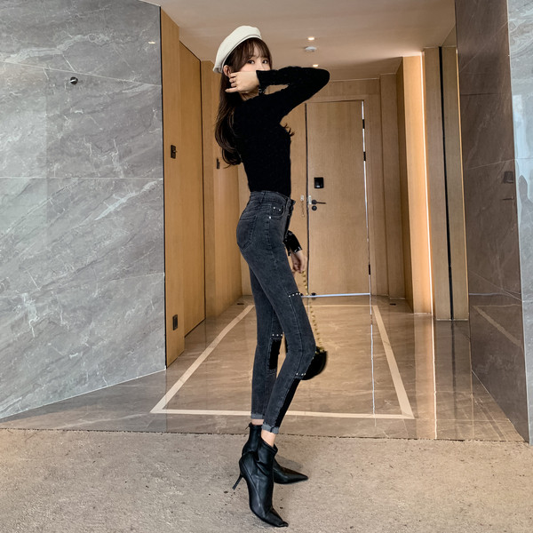 Sötét színű, testhezálló női farmer, magas derékkal és fémszegecsekkel