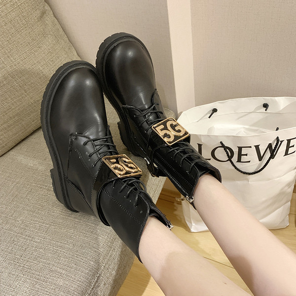 Cizmele moderne de piele de damă cu un element metalic sunt alb-negru