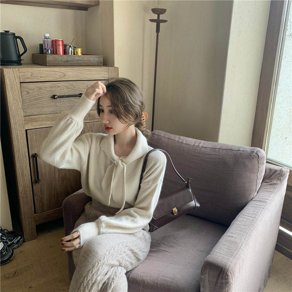 Vékony kötésből készült női blúz puffos ujjakkal és nyakkikötővel