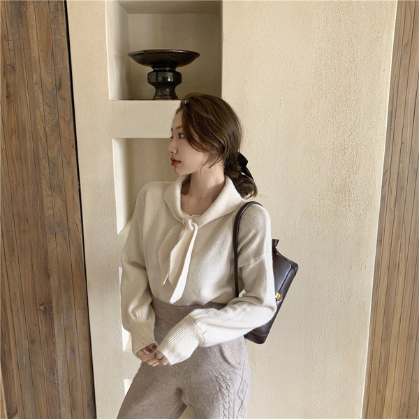 Vékony kötésből készült női blúz puffos ujjakkal és nyakkikötővel