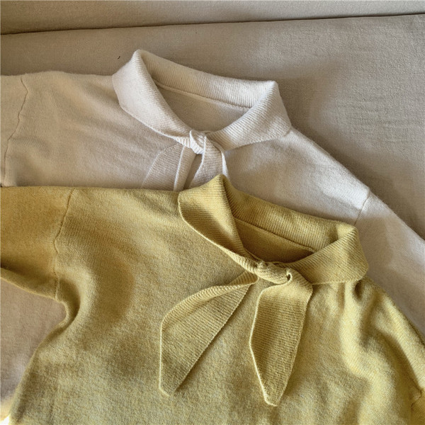 Vékony kötésből készült női blúz puffos ujjakkal és nyakkikötővel