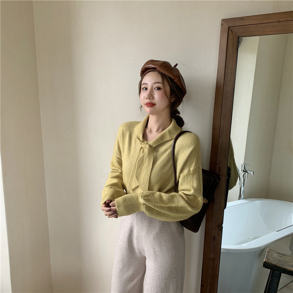 Vékony kötésből készült női blúz puffos ujjakkal és nyakkikötővel