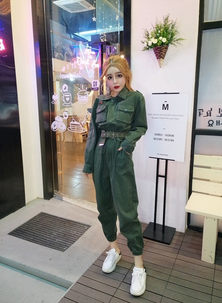 Modern női overál klasszikus gallérral és zsebekkel, övvel és a bokánál zöld színű gumival