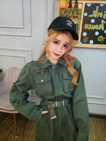 Modern női overál klasszikus gallérral és zsebekkel, övvel és a bokánál zöld színű gumival