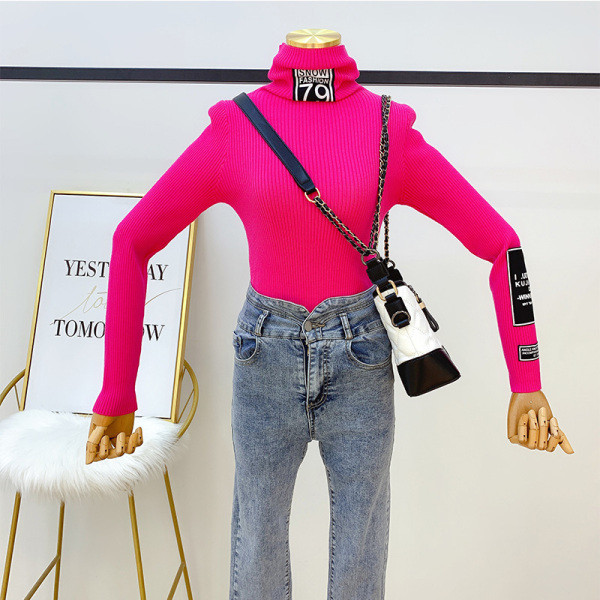 Női pulóver magas gallérral és kék, rózsaszín, bézs és fekete emblémával