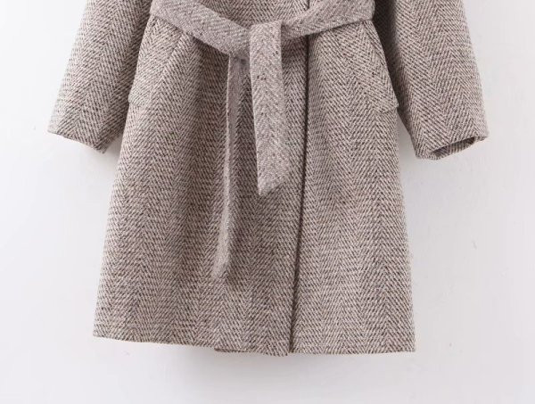 Hosszú, modern kabát aszimmetrikus rögzítéssel és szürke színű övvel