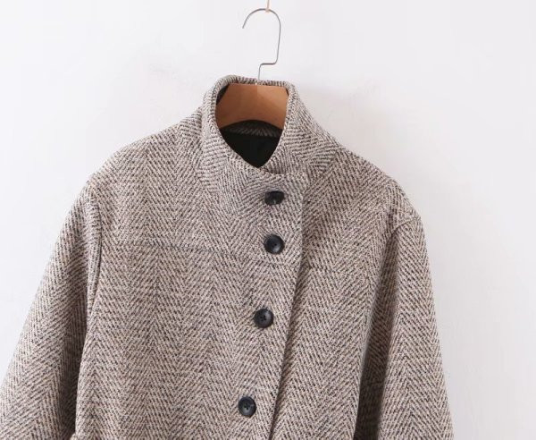 Hosszú, modern kabát aszimmetrikus rögzítéssel és szürke színű övvel