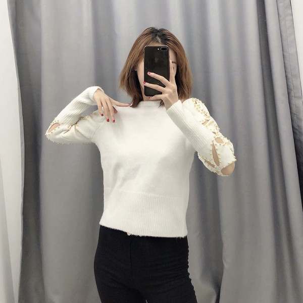 Modern testhezálló bézs színű pulóver kivágott részekkel és fém elemekkel az ujjakon