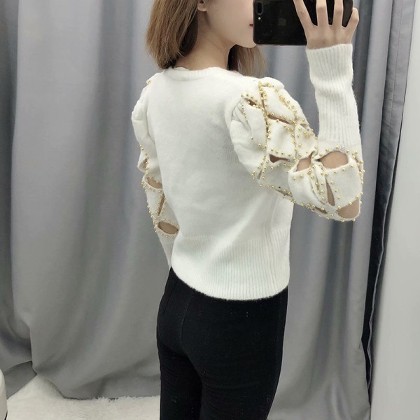 Modern testhezálló bézs színű pulóver kivágott részekkel és fém elemekkel az ujjakon