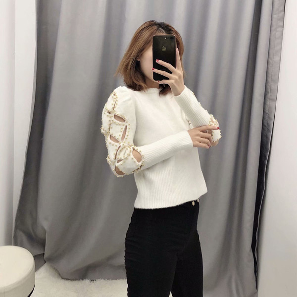 Modern testhezálló bézs színű pulóver kivágott részekkel és fém elemekkel az ujjakon