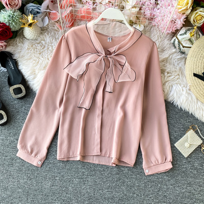 Stílusos női ing gallérján szalaggal és fekete, fehér, bézs és rózsaszín gombokkal