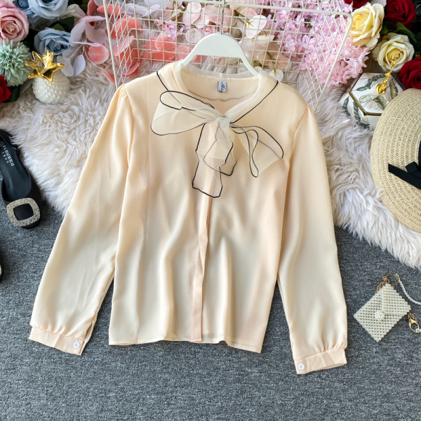 Stílusos női ing gallérján szalaggal és fekete, fehér, bézs és rózsaszín gombokkal