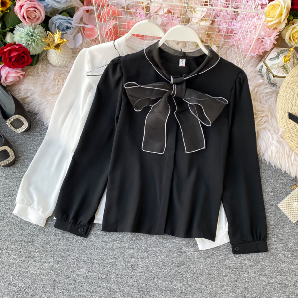 Stílusos női ing gallérján szalaggal és fekete, fehér, bézs és rózsaszín gombokkal