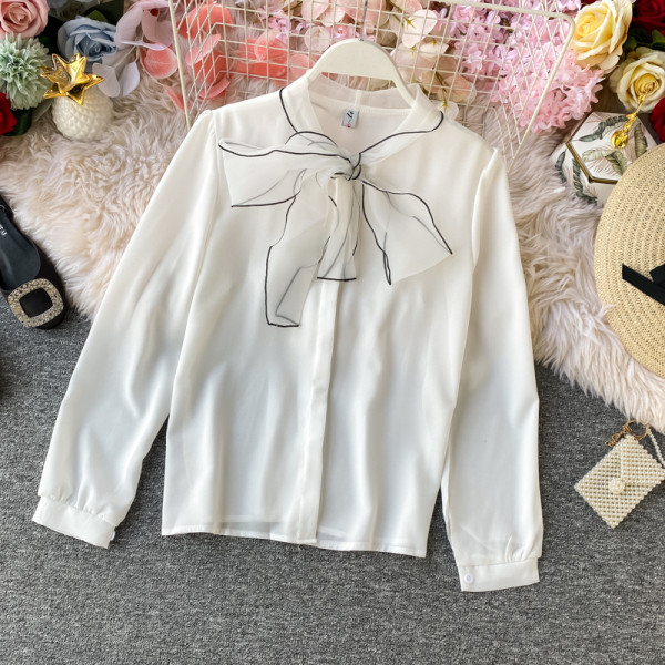 Stílusos női ing gallérján szalaggal és fekete, fehér, bézs és rózsaszín gombokkal