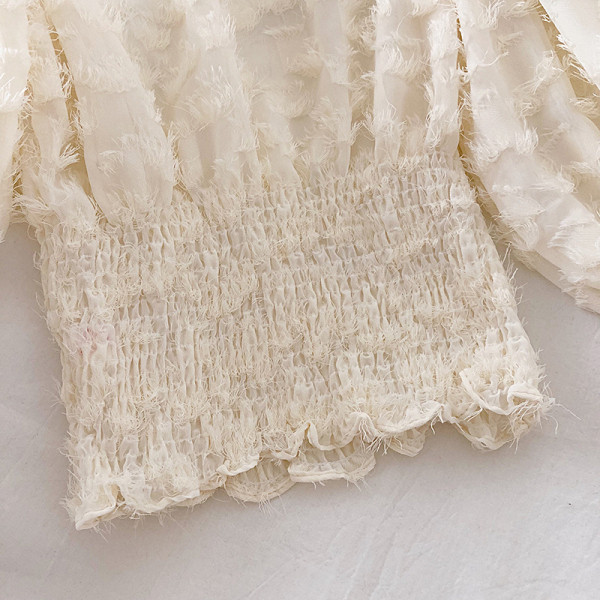 Bézs, fekete-fehér női blúz magas gallérral és bojttal