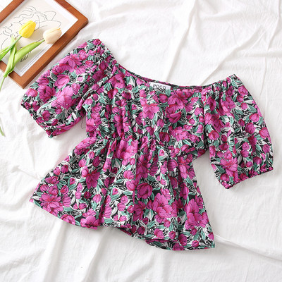 Színes női blúz csónakos nyakkivágással és virágmotívumokkal