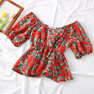 Színes női blúz csónakos nyakkivágással és virágmotívumokkal