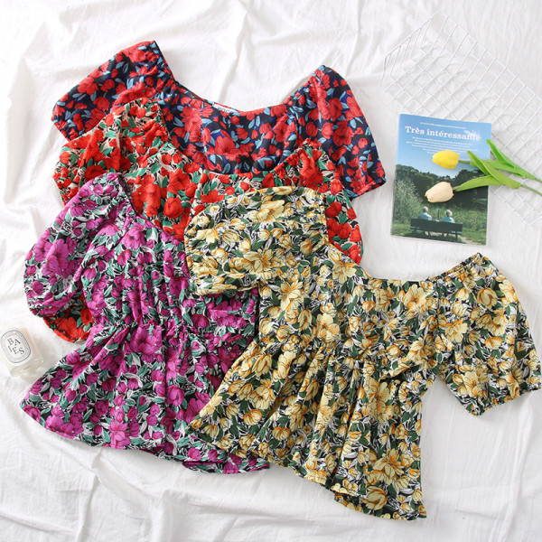 Színes női blúz csónakos nyakkivágással és virágmotívumokkal