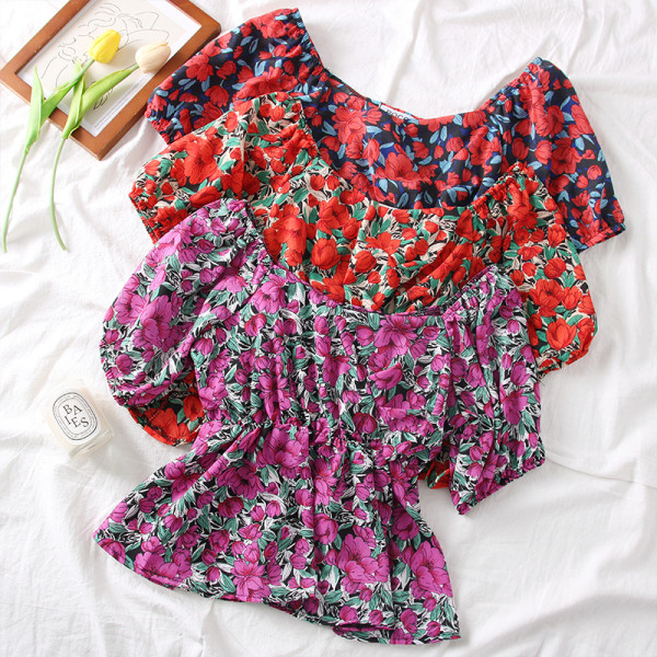 Színes női blúz csónakos nyakkivágással és virágmotívumokkal