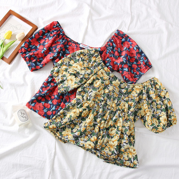 Színes női blúz csónakos nyakkivágással és virágmotívumokkal